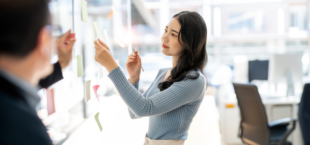 Young creative business people Creating Project Plan on Office Wall with Paper Notes.